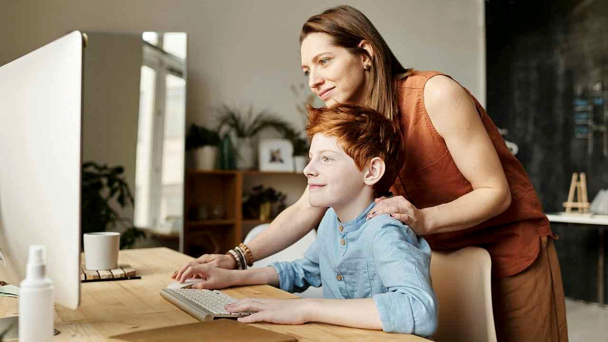 A mother watches her son surf the web.
